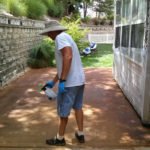 worker sealing a concrete patio with spray sealant